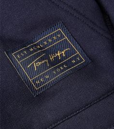 a label on the back of a blue suit with gold lettering and a black background