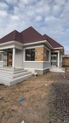 a house being built in the middle of a dirt lot with rocks and gravel around it