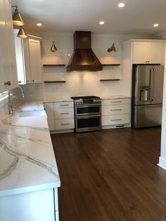 an empty kitchen with white cabinets and wood floors