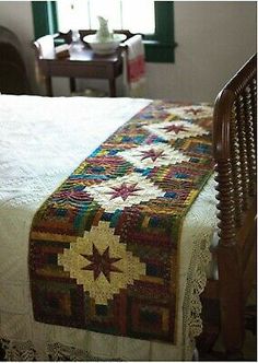 a bed with a quilt on top of it in a room next to a window