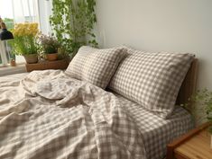 a bed with two pillows and some plants in the window sill next to it