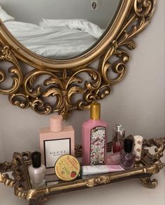 an ornate gold shelf with cosmetics and perfumes on it in front of a mirror