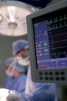 two surgeons in scrubs operating on an electronic monitor