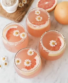 four glasses filled with pink grapefruit and garnished with flowers