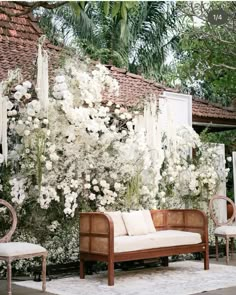 an outdoor seating area with white flowers on the wall and hanging curtains in the background