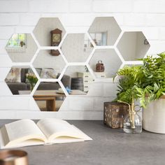 an open book sitting on top of a table next to a potted plant and mirror