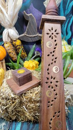 a wooden clock sitting on top of a table next to hay and pumpkins in the background