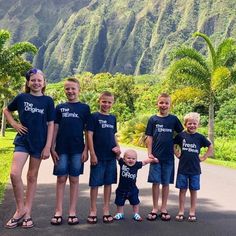 a group of children standing next to each other in front of a lush green hillside