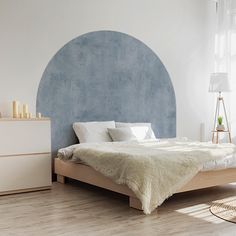 a bedroom with a bed, dresser and window in the corner that has a blue circle painted on the wall