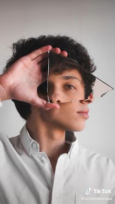 a man is holding his head with scissors in front of his face and looking at the camera