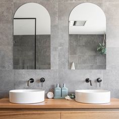 two white sinks sitting next to each other on top of a wooden counter in a bathroom