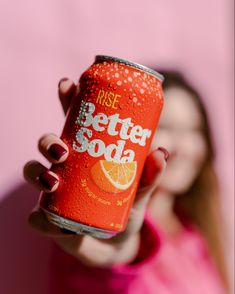 a woman holding up a can of soda