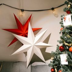 a red and white star hanging from the ceiling next to a christmas tree