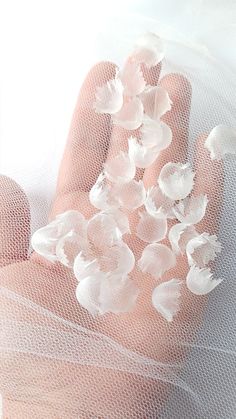 a person's hand with white flowers on it and mesh netting around the palm