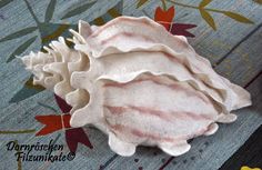 a white flower sitting on top of a wooden table next to an orange and red leaf