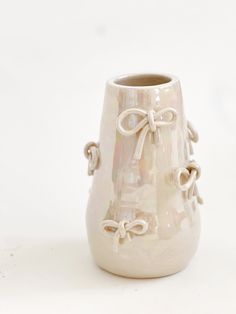 a white vase sitting on top of a table next to a cup with a bow