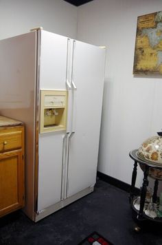 a white refrigerator freezer sitting in a kitchen next to a wooden cabinet and counter