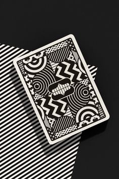 a black and white playing card sitting on top of a striped table cloth with an intricate design