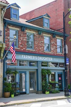 an american flag is hanging on the outside of a store in front of a brick building