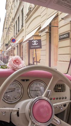 the interior of a car with pink trim and steering wheel, in front of a building