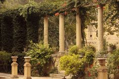 an old building with columns and flowers growing on it