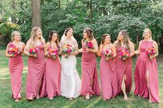 a group of women standing next to each other holding bouquets in front of trees