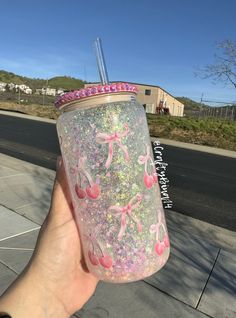 a hand holding up a pink and green glittered cup