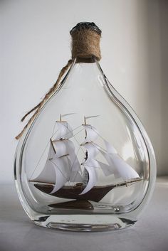 a sailboat in a glass bottle with rope hanging from it's top and bottom