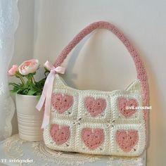 a crocheted purse sitting on top of a table next to a potted plant