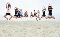 a group of people doing yoga on the beach