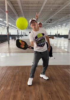 a man standing on top of a hard wood floor next to a yellow frisbee