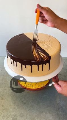 someone is cutting into a chocolate cake with a knife and fork on top of it