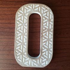 the letter o is made out of wood and has an intricate pattern on it's surface