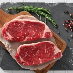 two pieces of raw meat sitting on top of a cutting board