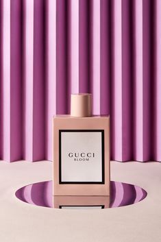 a bottle of perfume sitting on top of a table next to a purple striped wall