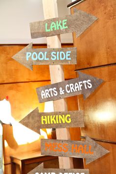 a wooden sign with many different colored signs on it's sides that read pool side arts and crafts making mess hall