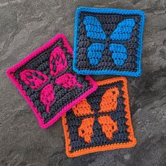 three crocheted coasters with butterfly designs on them sitting on the ground next to each other