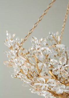 a gold chandelier with crystal flowers and leaves hanging from it's sides