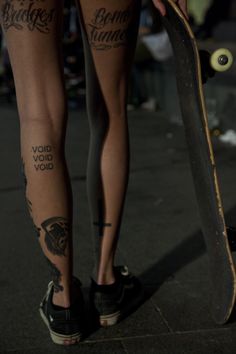 a person with tattoos on their legs holding a skateboard