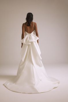 the back of a woman's white wedding dress with a large bow on it