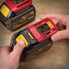 two red and yellow power tools being held by someone's hand