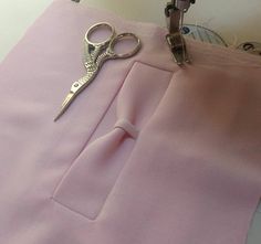 a pair of scissors on top of a pink piece of cloth next to a sewing machine