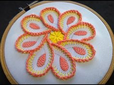 a close up of a embroidery on a piece of cloth with an orange and yellow flower