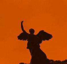 an angel statue is silhouetted against the orange sky