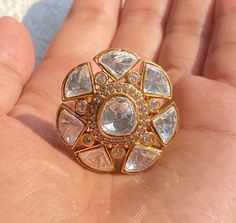 a hand holding a gold ring with clear stones on it's center and sides