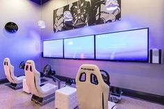 the game room is decorated with pink and white gaming chairs, as well as three large screens