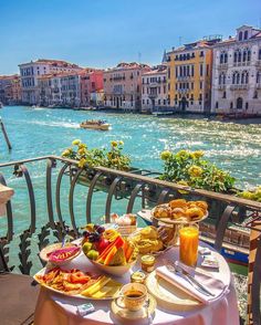 an outdoor table with food and drinks on it overlooking the water in venice, italy