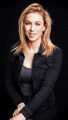 a woman sitting on top of a chair in front of a black background with her legs crossed