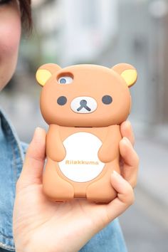 a woman holding up a phone case with a bear on it