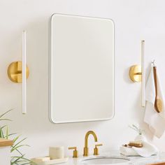 a bathroom with a sink, mirror and gold faucet